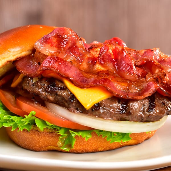 Fred's Burger with bacon, cheese, lettuce, tomato, and onion on a toasted bun.