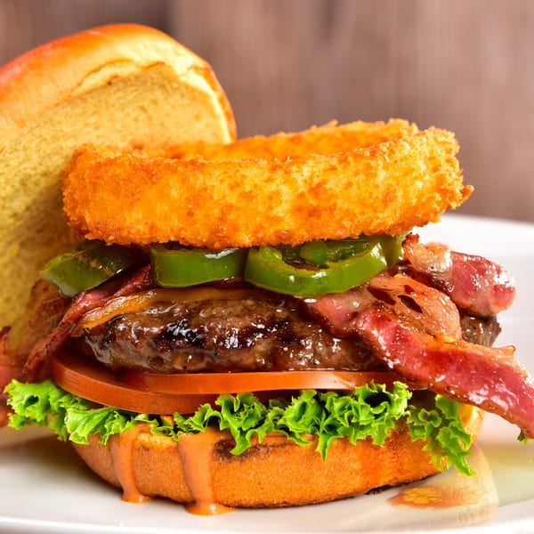 A Fred's Burger with bacon, jalapeños, onion rings, lettuce, tomato, and special sauce.