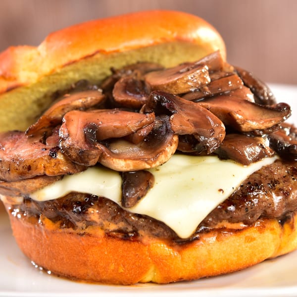 Fred's Burger: a juicy mushroom swiss burger on a toasted bun, close-up.
