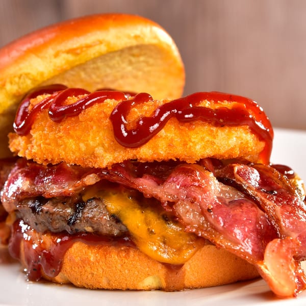Fred's Burger with bacon, melted cheese, and a crispy onion ring drizzled with BBQ sauce.