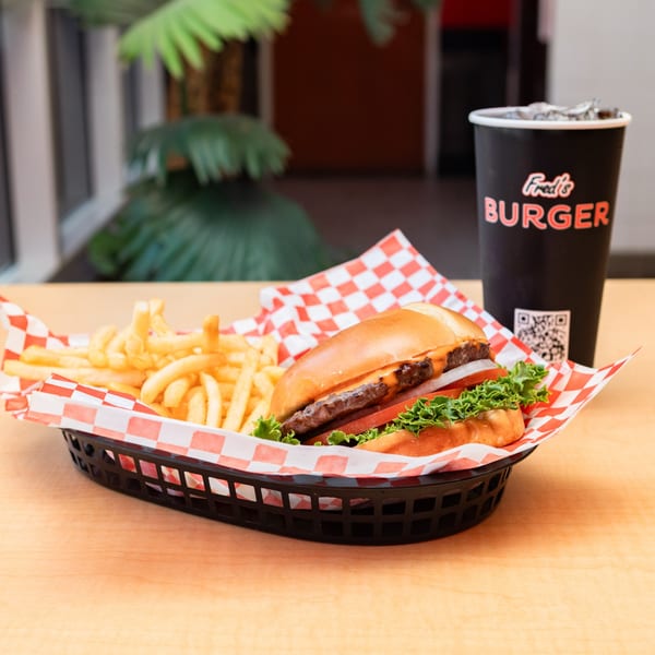 Fred's Burger combo with a cheeseburger, fries, and a drink on a wooden table.