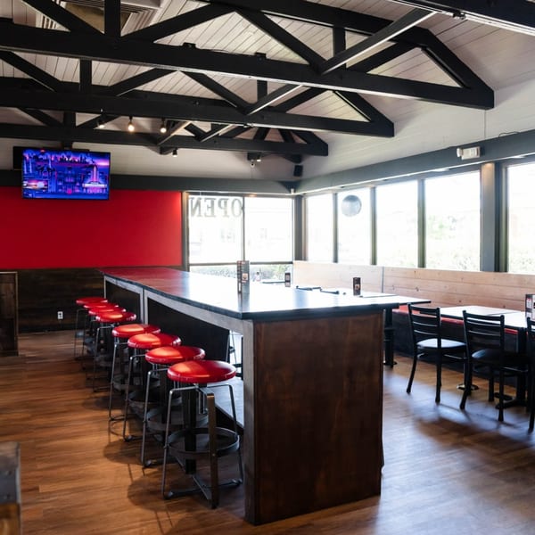 Interior of Fred's Burger with a long bar, red stools, red accent wall, and large windows.
