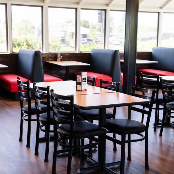 Interior of Fred's Burger restaurant with empty tables, chairs, and red and black booths.